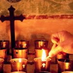 Worshiper Lighting Votive Candle on Altar